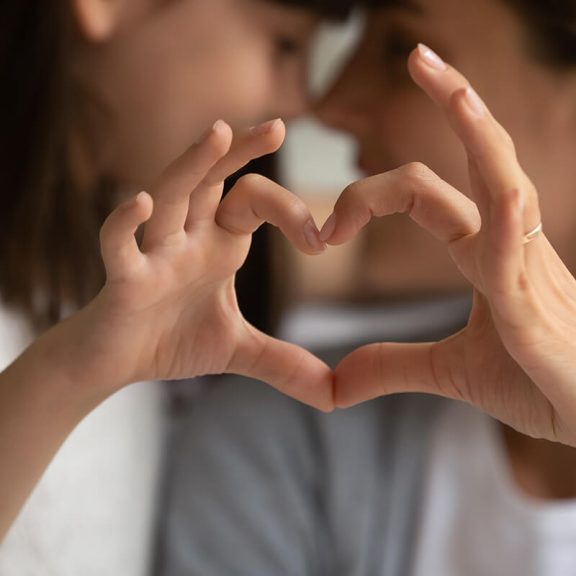 adult and child making heart out of their hands