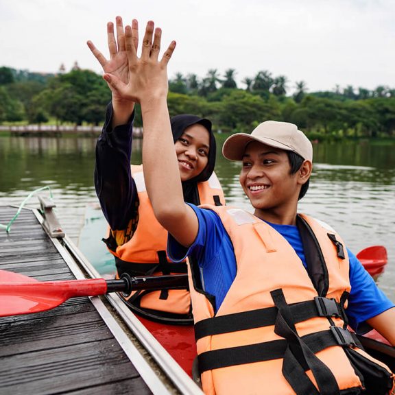 two teenagers in a canoe giving a high five