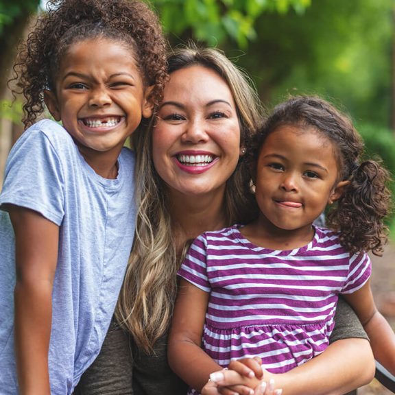 woman with two younger girls smiling and making silly faces