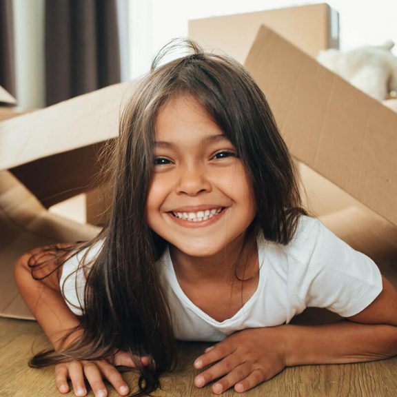 little girl playing with cardboard boxes smiling