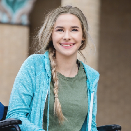 girl with long blonde hair braided smiling in wheelchair