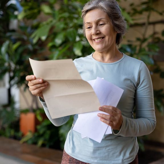 Older woman holding paper from the mail smiling