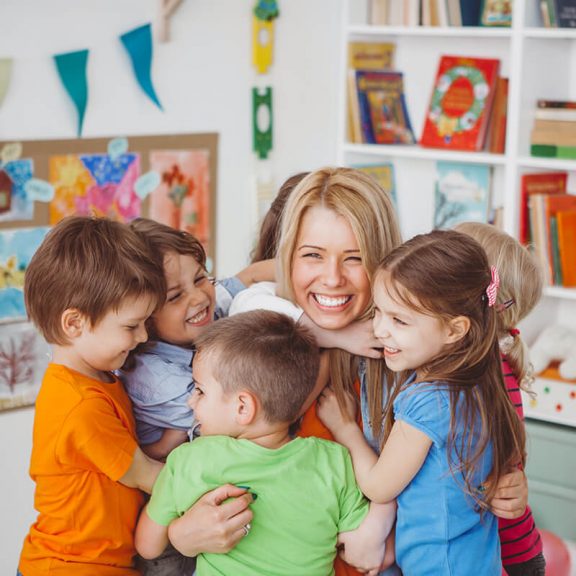 woman surrounded by children giving her a group hug